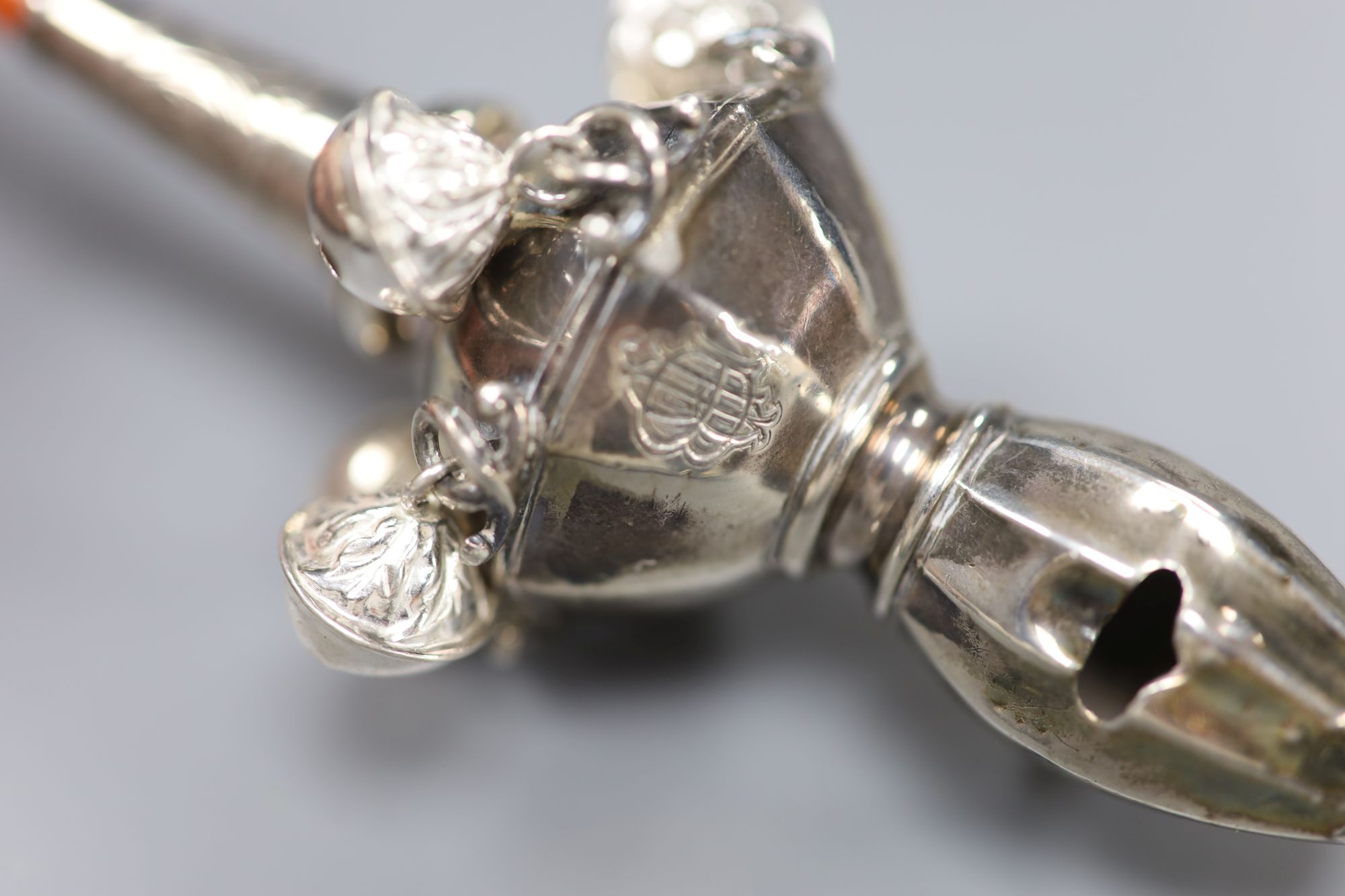 A George V silver childs rattle with coral teether and six bells, Crisford & Norris, Birmingham, 1911, 13cm.